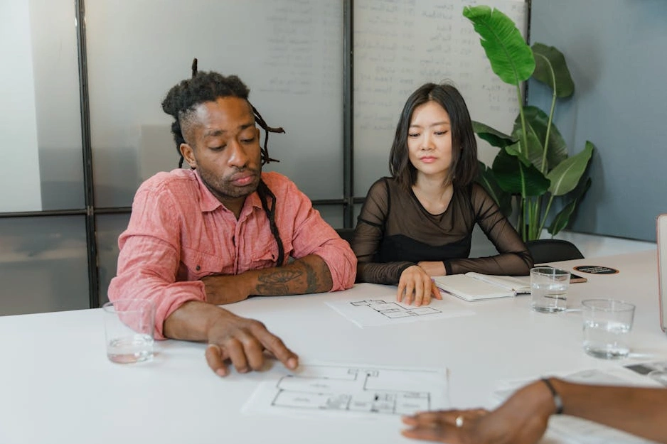 Two professionals collaborating over a laptop displaying a project plan with Gantt charts.